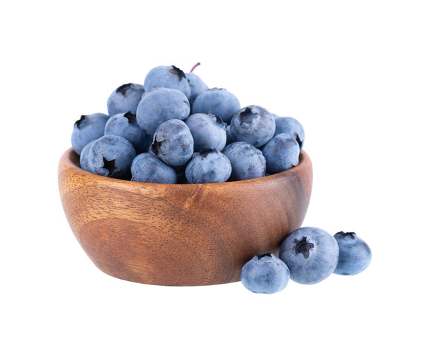 Fresh blueberry in wooden bowl, isolated on white background. Bilberry or whortleberry. Clipping path - Photo, image