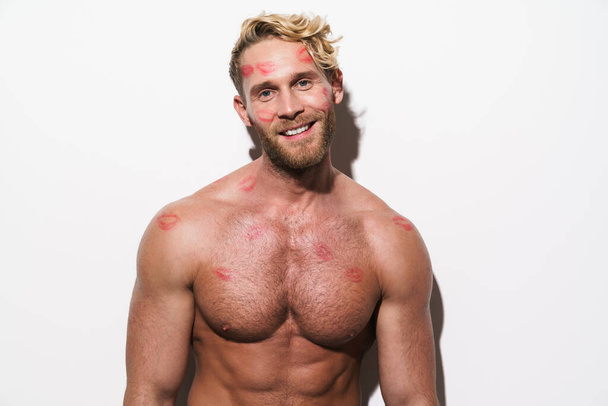 White shirtless man with lipstick marks smiling and looking at camera isolated over white wall - Foto, imagen