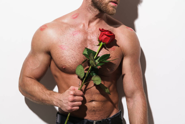Shirtless blonde man with lipstick smudge while holding red rose isolated over white background - Foto, Bild