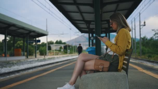 Kobieta siedząca i czekająca na pociąg. - Materiał filmowy, wideo