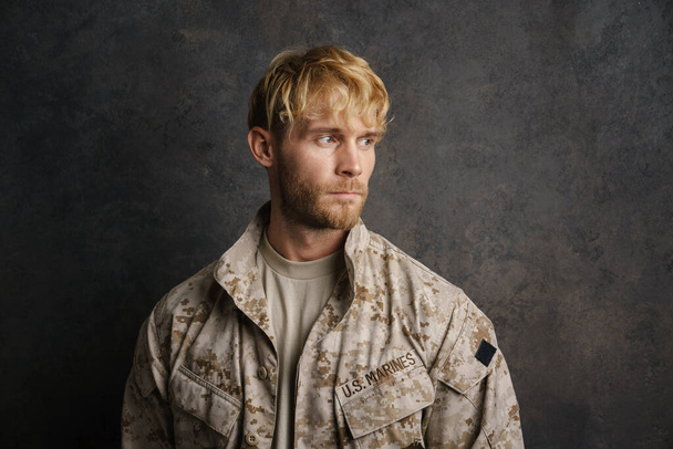 White military man wearing uniform posing and looking aside isolated over grey wall - Foto, imagen