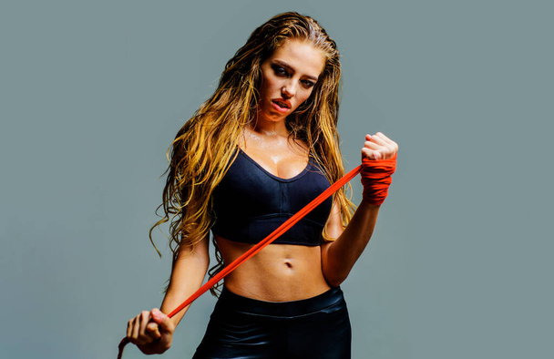 Sportowa kobieta przygotowująca się do walki. Wojowniczka w sportowej bluzce z czerwonymi bandażami. Kobiecy bokser - Zdjęcie, obraz