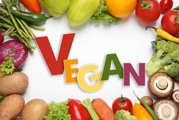 Word Vegan and fresh vegetables on white background, flat lay - Photo, Image