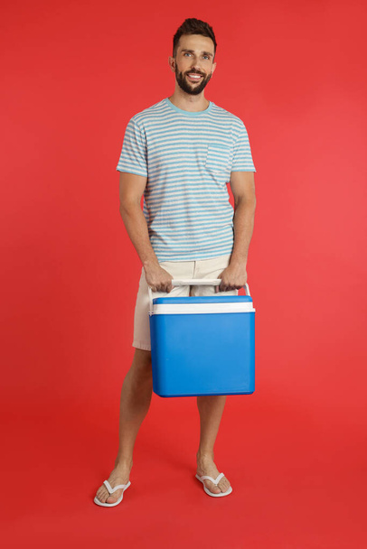 Happy man with cool box on red background - Photo, image