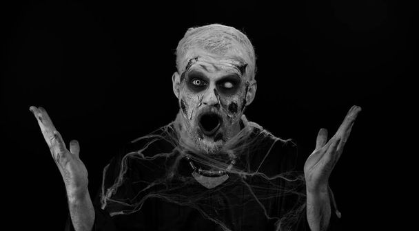 Aman Tanrım, vay canına. Korkunç adam Cadılar Bayramı 'nda yalnız başına kanlı zombi makyajıyla büyük gözlerle kameraya bakarken şaşkınlıkla el kaldırıyor, ani zaferden şok oluyor. # Heyecanlı, şaşkın, uğursuz, ölümsüz adam - Fotoğraf, Görsel