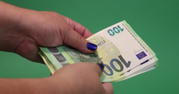 Adult female hands holding and counting 100 and 200 euro banknotes on a green studio background. Concept of economy, financial planning and prosperity - Materiał filmowy, wideo