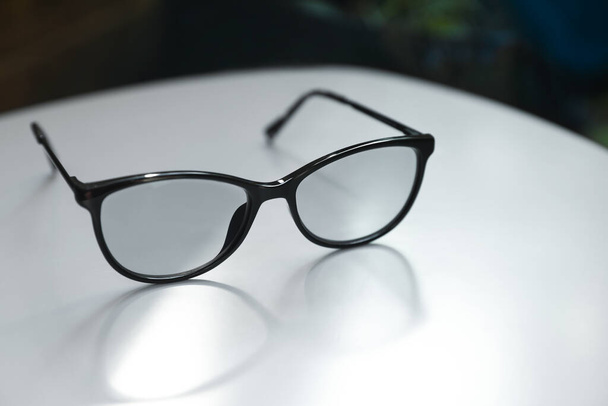 Stylish black eye glasses on white table, closeup - Zdjęcie, obraz