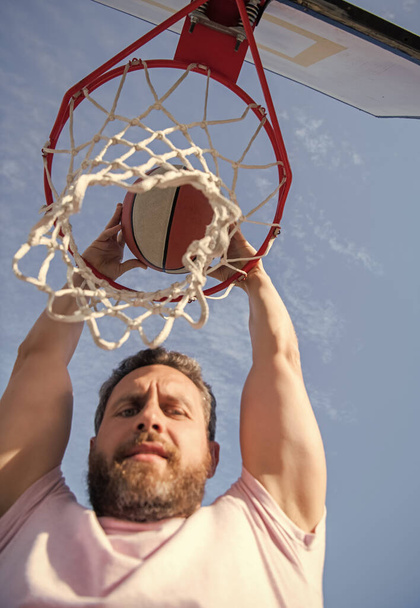 летняя активность. человек с баскетбольным мячом на площадке. профессиональный баскетболист тренируется на открытом воздухе. У парня есть спортивная мотивация. спорт и хобби. окунуться в корзину. slam dunk in motion. - Фото, изображение