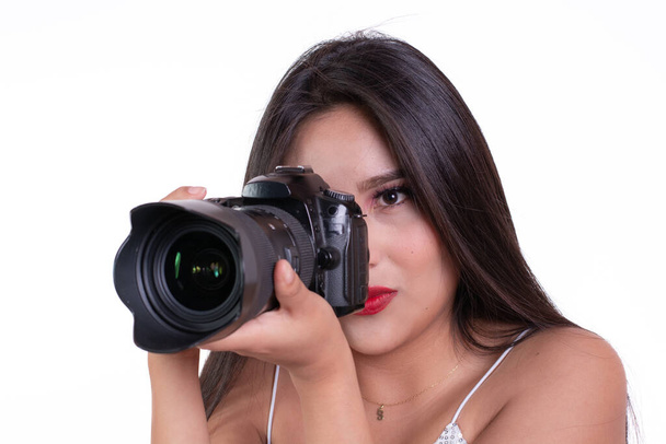 латиноамериканська дівчина тримає камеру, прикидаючись фотографом, ізольована на білому тлі, концепція курсу фотографії
 - Фото, зображення
