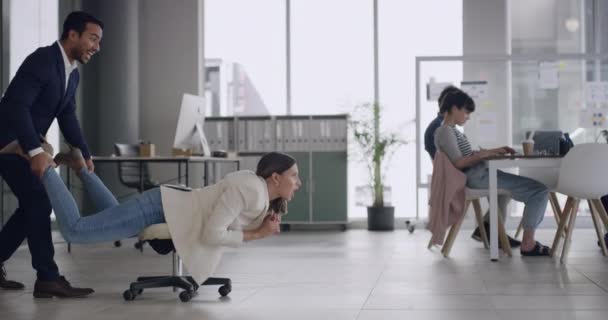 An extremely happy partner enjoying success by acting like swimming on the office chair. Two young office colleagues having fun in the office enjoying themselves together in a very different way - Filmati, video