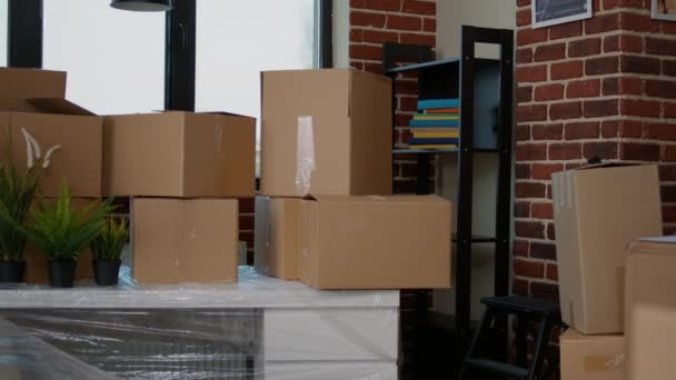 Niemand in de lege woonkamer met kartonnen verpakkingen in een nieuw huis, meubelstukken in een stapel kartonnen dozen. Geen mensen in huis met pakketlading om in te trekken, onroerend goed. - Video
