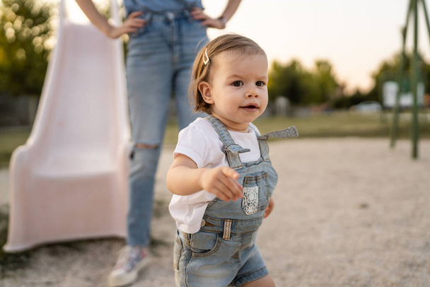 small caucasian girl little toddler standing by her mother in park in summer day real people family concept childhood growing up copy space - Foto, Imagen