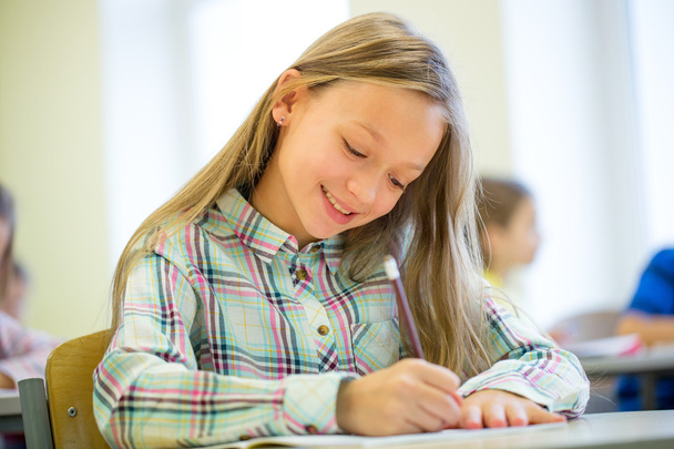 усміхнена школярка пише тест в класі
 - Фото, зображення