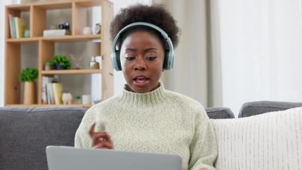 A confident, professional and casual business woman wearing headphones talking on a video call while working from home. Social female on laptop explains something to a friend, client or colleague - Materiał filmowy, wideo