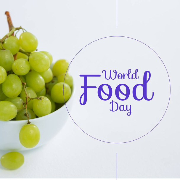 Image of world food day over grapes in bowl on white background. Food, nutrition, agriculture, health and food production concept. - Photo, Image