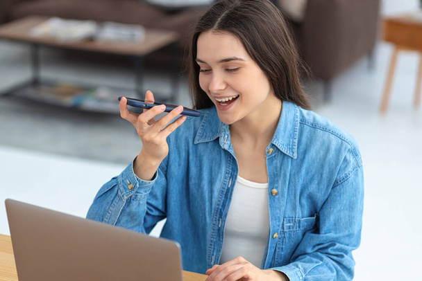 Young Caucasian woman freelancer or office employee talking on mobile phone while working at home office or in coworking while sitting at workplace - Photo, Image