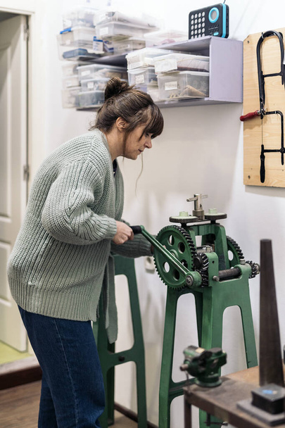 Concentrated craftswoman working and using special machine in jewelry workshop. - Zdjęcie, obraz