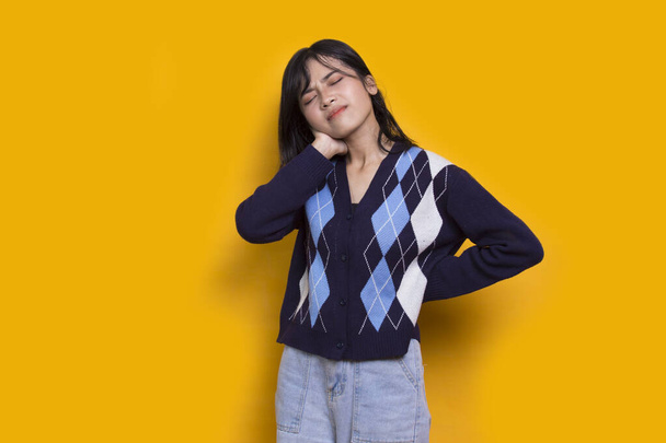 beautiful asian young woman with sore throat neck and shoulder pain isolated on yellow background - Foto, afbeelding