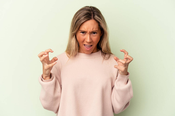 Young caucasian woman isolated on green background screaming with rage. - Photo, Image