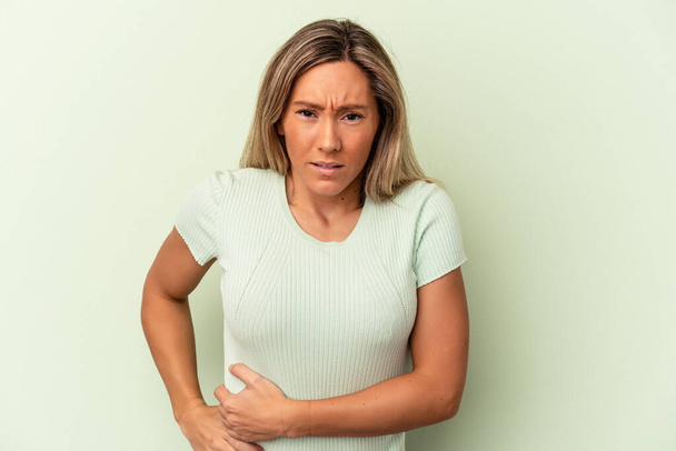 Young caucasian woman isolated on green background having a liver pain, stomach ache. - Photo, Image