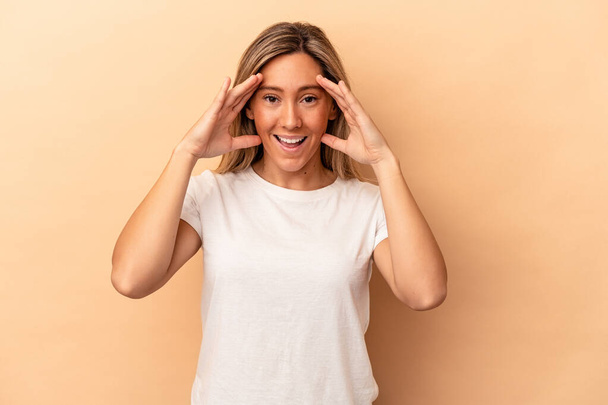 Young caucasian woman isolated on beige background receiving a pleasant surprise, excited and raising hands. - Photo, Image