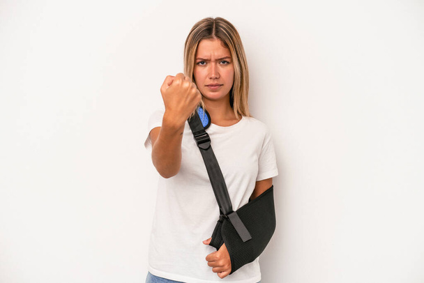 Young caucasian woman with broken hand isolated on white background showing fist to camera, aggressive facial expression. - Fotó, kép