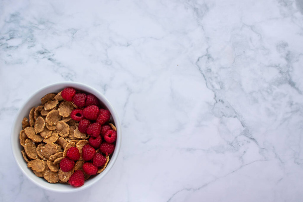 Bowl of multigrain cereal with fresh raspberry berries on marble table background. Healthy diet breakfast. Top view, flat lay, copy space - Foto, imagen