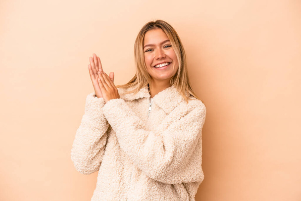 Young caucasian woman isolated on beige background feeling energetic and comfortable, rubbing hands confident. - Fotoğraf, Görsel