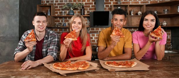 Gençler mutfakta lezzetli pizzalar yiyorlar. - Fotoğraf, Görsel