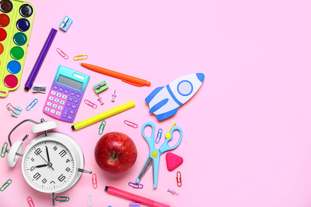 Papieren raket met schoolbriefpapier, wekker en appel op roze achtergrond - Foto, afbeelding