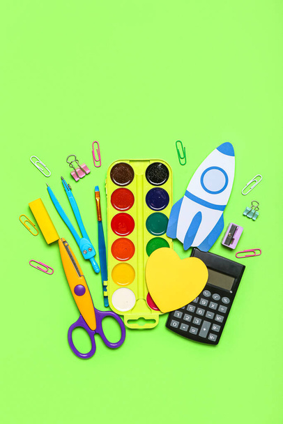 Paper rocket with school stationery on green background - Foto, afbeelding