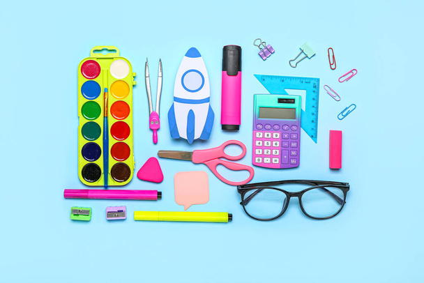 Paper rocket with school stationery and eyeglasses on blue background - 写真・画像