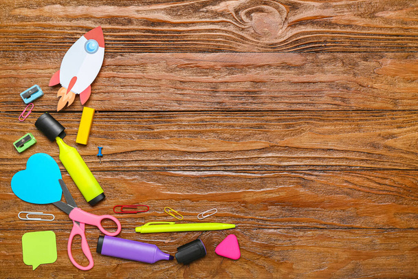 Paper rocket with school stationery on wooden background - Photo, image