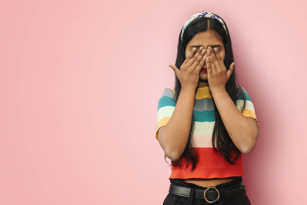 Young Indian Asian scared girl posing isolated covering eyes with hands. Confused girl close eyes with palms ignoring something. See no evil concept. Mock up copy space. - Photo, Image