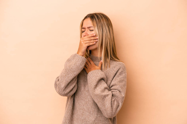 Young caucasian woman isolated on beige background suffers pain in throat due a virus or infection. - Фото, изображение