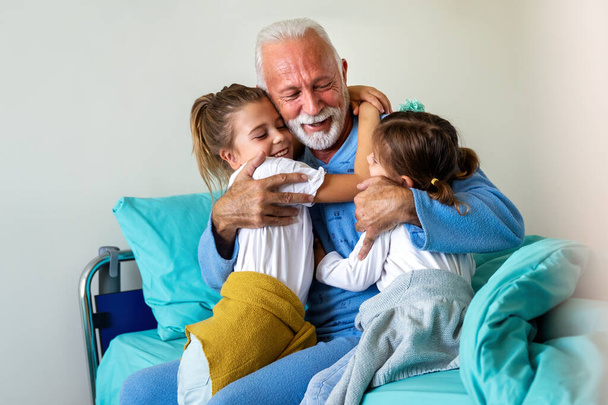 Happy children with senior grandfather laughing and enjoying leisure time together. Family, support, fun concept - Photo, Image