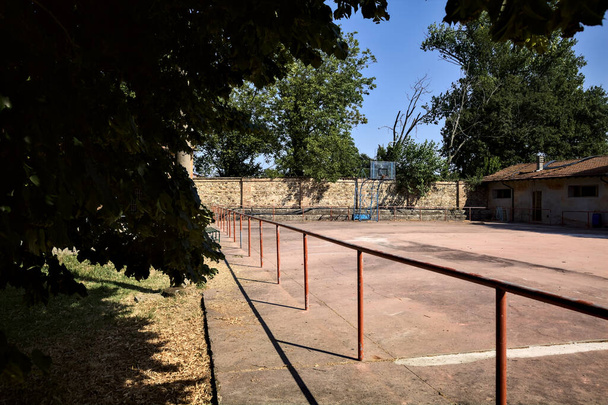 Lege basketbalveld begrensd door een rail op een zonnige dag - Foto, afbeelding