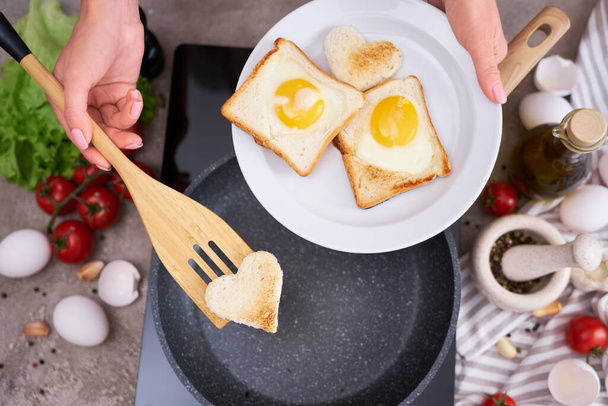 Fried egg Toasts with heart shaped holes on frying pan. - Foto, Imagem