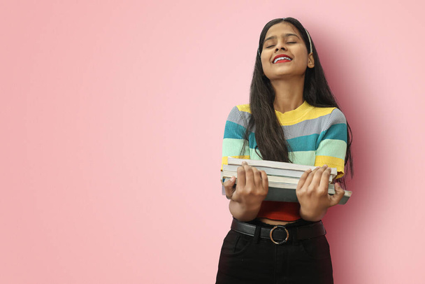 Izgatott fiatal indiai lány diák pózol iszlolált gazdaság tankönyvek szeretettel olvasni, vagy töltsön szabadidőt könyvek, mint egy hobbi és pihentető csukott szemmel és állát fel. - Fotó, kép