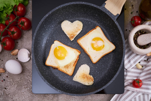 Fried egg Toasts with heart shaped holes on frying pan. - Fotoğraf, Görsel