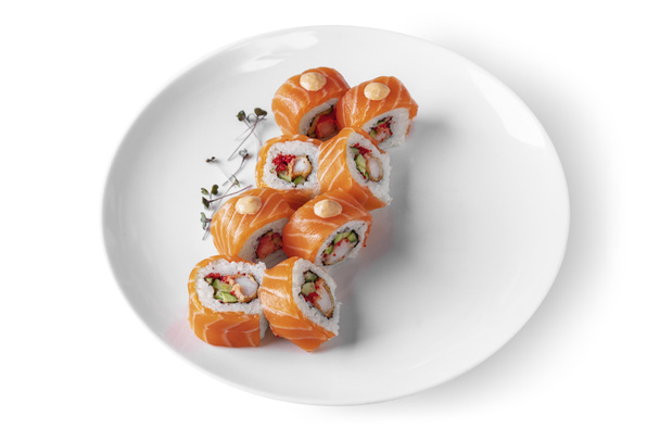 Roll with rice, salmon, shrimp, cucumber, avocado, mung bean salad, tobiko caviar, nori, sauce and Philadelphia cheese in a plate on a white background - Foto, afbeelding