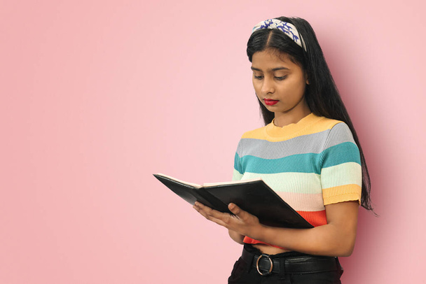 Portrait of young cute indian asian girl standing and posing isolated reading books expressing positive emotions. Education concept. Mock up copy space - Photo, Image