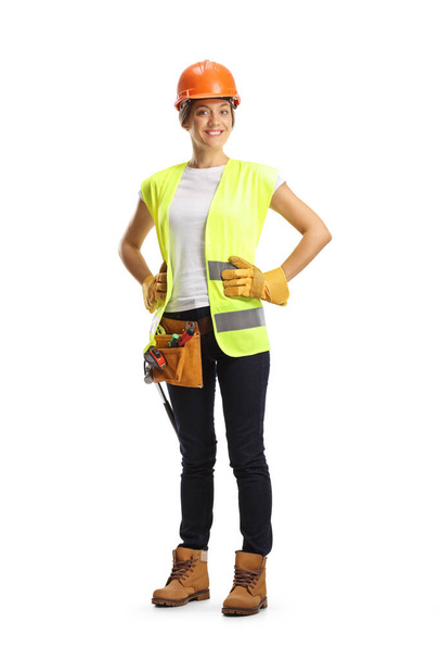 Full length portrait of a female construction worker wearing a helmet and a tool belt isolated on white background - Photo, Image