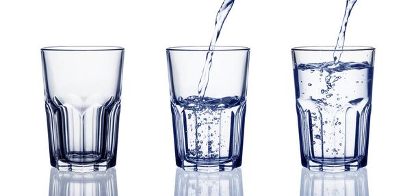Water pouring into glass isolated on white background, toned blue. Set of glasses with water. - 写真・画像