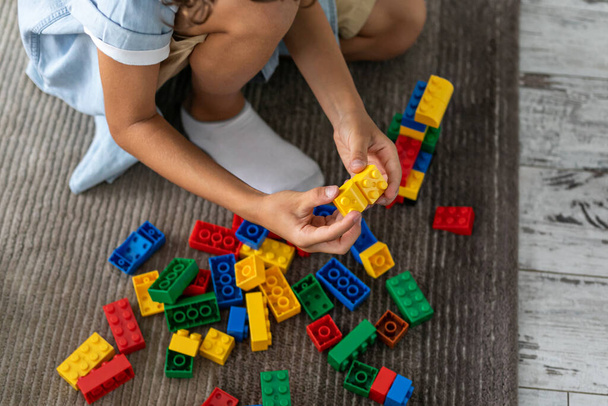 Μικρό αγοράκι παίζει με πολύχρωμα πλαστικά μπλοκ στο σπίτι σαλόνι για χαλί κτίριο δημιουργικό παιχνίδι, φαντασία - Φωτογραφία, εικόνα