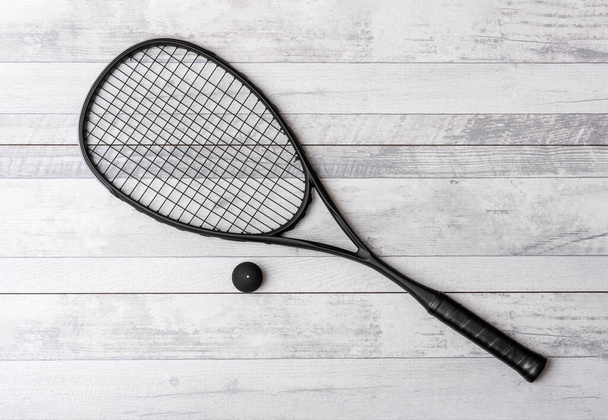 Raqueta de squash negro y pelota en cancha gris. Cartel de tema deportivo horizontal, tarjetas de felicitación, encabezados, sitio web y aplicación - Foto, imagen