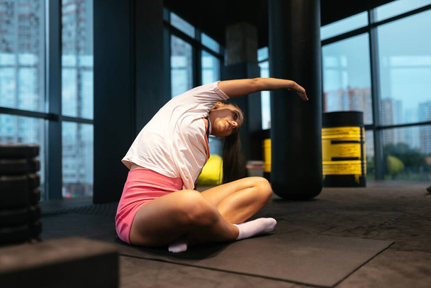 Young sporty woman practicing yoga, working out, wearing sportswear, indoor full length, yoga studio - 写真・画像