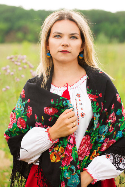 Eine schöne Ukrainerin in Tracht mit Schal auf einem Feld - Foto, Bild