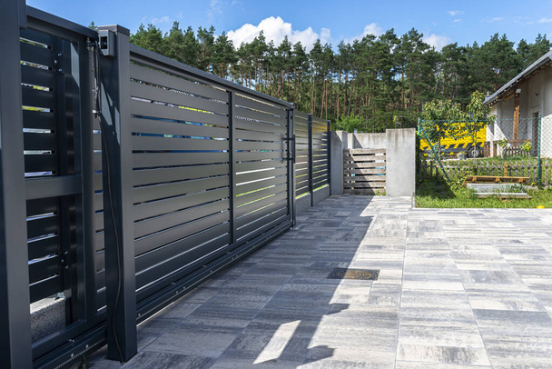 Modern panel fencing in anthracite color, visible sliding gate to the garage as well as a handle and a lock. - Foto, afbeelding