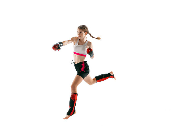 Power and energy. One sportive teen-girl, professional MMA fighter in action, motion isolated on white background. Concept of sport, competition, action, health. Copy space for ad. - Photo, Image
